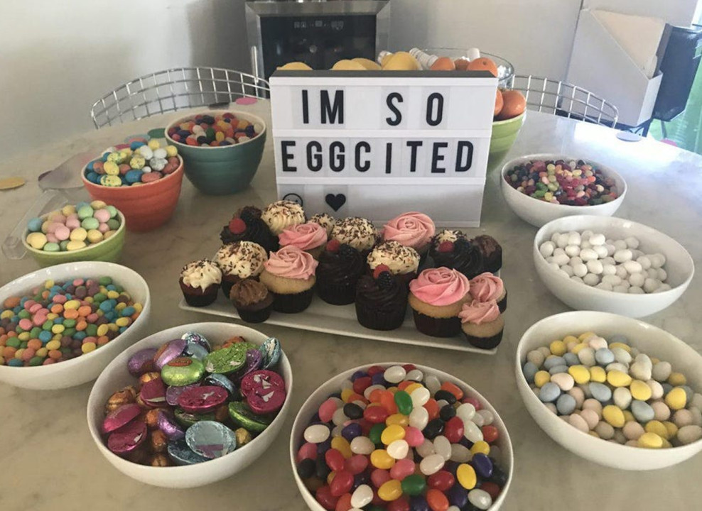 На фото: тарелки с конфетами, в центре табло с надписью «I'm so eggcited»