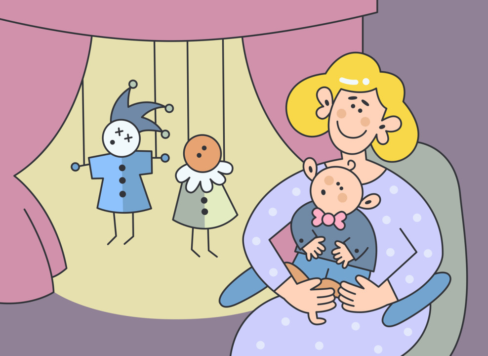 Мама с ребенком на руках смотрят театр кукол. Иллюстрация НЭН